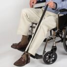 A man in a wheelchair with his foot on the handle of a cane.